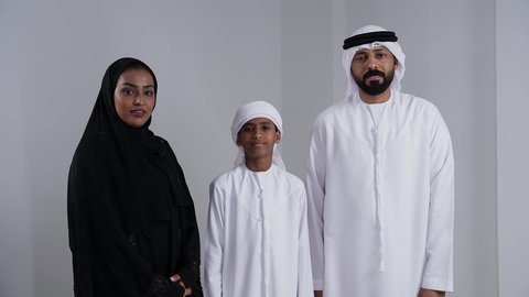 الاستقرار العائلي في التمليك والاسكان, الالتزام بالقواعد والقوانين الأسريه، بورتريه لرجل عربي خليجي اماراتي يرتدي الكندورة و الغتره يحمل مفتاح المنزل الجديد برفقة زوجته و ابنه، ايماءات تدل على السعادة والفرح ، أساسيات العائلة الاماراتية السعيده، خلفية بيضاء