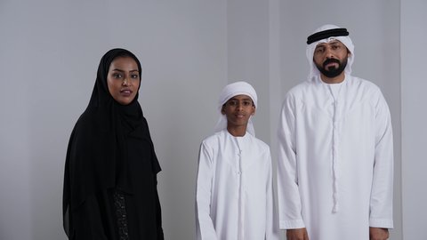 الإشارة إلى عنصر ما, التوضيح والدلالة لمكان محدد, بورتريه لرجل عربي خليجي اماراتي يرتدي الكندورة و الغتره يشير الى شي ما برفقة زوجته و ابنه ، تحديد موقع شيء معين، خلفية بيضاء