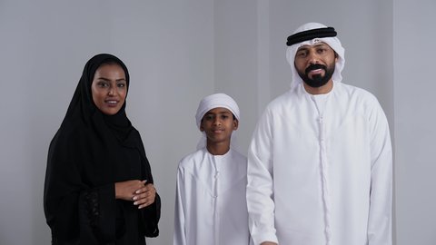 الحصول على رخصة القيادة, استلام وتسليم المفاتيح، الأجواء العائلية المليئة بالحب, بورتريه لرجل عربي خليجي اماراتي يرتدي الكندورة و الغتره يمسك بيدية مفتاح التحكم عن بعد و ينظر الى الكاميرا بايماءات السعادة و السرور برفقة زوجته و ابنه, خلفية بيضاء