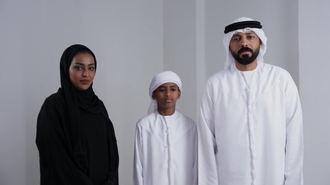 الحماس لامتلاك سيارة جديدة, تعابير الموافقة و القبول, الأجواء العائلية المليئة بالحب, بورتريه لرجل عربي خليجي اماراتي يرتدي الكندورة و الغتره يمسك بيدية مفتاح التحكم عن بعد و ينظر الى الكاميرا بايماءات السعادة و السرور, خلفية بيضاء