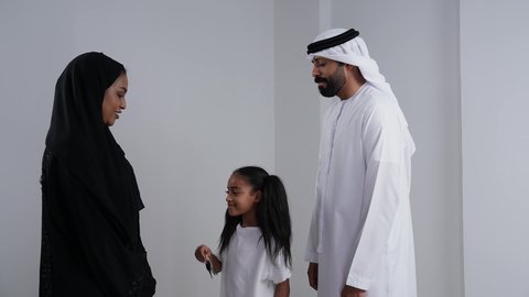 الأجواء العائلية المليئة بالحب, الشعور بالفرح لامتلاك سيارة جديدة, بورتريه لبنت عربية خليجيه اماراتية ترتدي الزي الكاجوال تمسك بيديها مفتاح التحكم عن بعد و تنظر الى والديها بايماءات السعادة و السرور, خلفية بيضاء