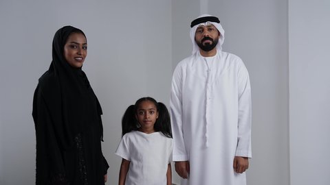 Expressions of joy and happiness, success and achieving goals, an Emirati Gulf Arab family dressed in traditional attire looking at the camera with facial and hand gestures indicating victory and triumph, white background.