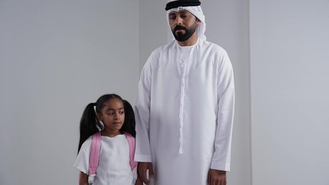 التجهيز لبداية العام الدراسي, ايماءات المشي و الذهاب, الاستعداد للذهاب الى المدرسة, موسم العوده للمدارس, بورتريه لبنت عربية خليجية اماراتية  تحمل الحقيبة المدرسية برفقة والدها, الرغبة في طلب العلم، خلفية بيضاء