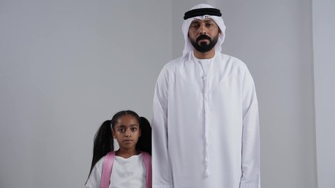 ايماءات المشي و الذهاب, الاستعداد للذهاب الى المدرسة, موسم العوده للمدارس, التجهيز لبداية العام الدراسي, بورتريه لبنت عربية خليجية اماراتية  تحمل الحقيبة المدرسية برفقة والدها, الرغبة في طلب العلم، خلفية بيضاء