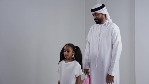 موسم العوده للمدارس, التجهيز لبداية العام الدراسي, بورتريه لبنت عربية خليجية اماراتية  تحمل الحقيبة المدرسية برفقة والدها,الاستعداد للذهاب الى المدرسة, الرغبة في طلب العلم، خلفية بيضاء