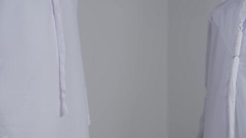 مفهوم الرابطة الأبوية والترابط الأسري, تحمل المسؤولية والاعتناء بالأولاد، الحب والعطف على الأبناء، بورتريه مقرب ليد رجل عربي خليجي اماراتي يرتدي الكندورة  يسمك بيد ابنه، خلفية بيضاء