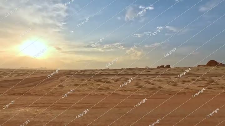 منظر من السيارة أثناء القيادة في منطقة الحجر الأثرية، صحراء مسطحة مع القليل من الأشجار الصغيرة.