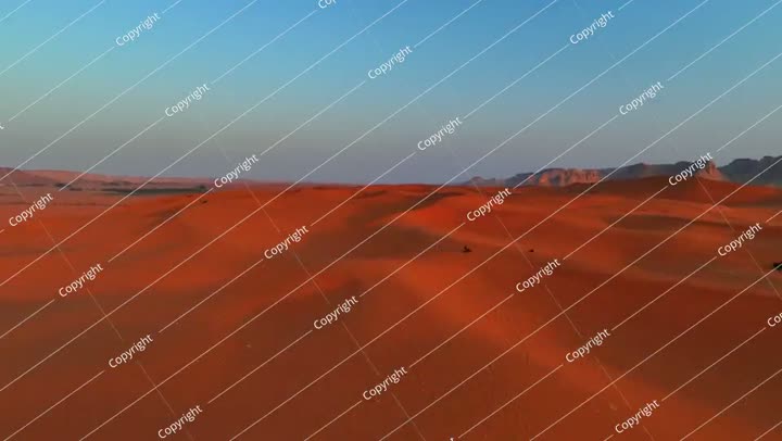 جويًا: لقطة أمامية من طائرة بدون طيار لشخص يقود دراجة رباعية على كثبان رملية حمراء مقابل