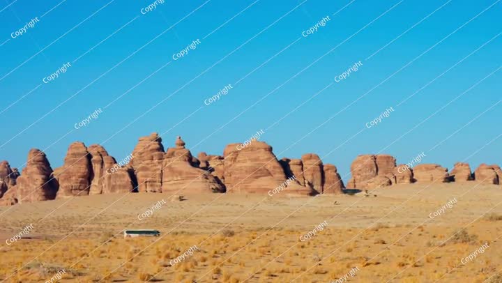 Car and bus carrying tourist IN the Hegra site with rock mountain in background.
