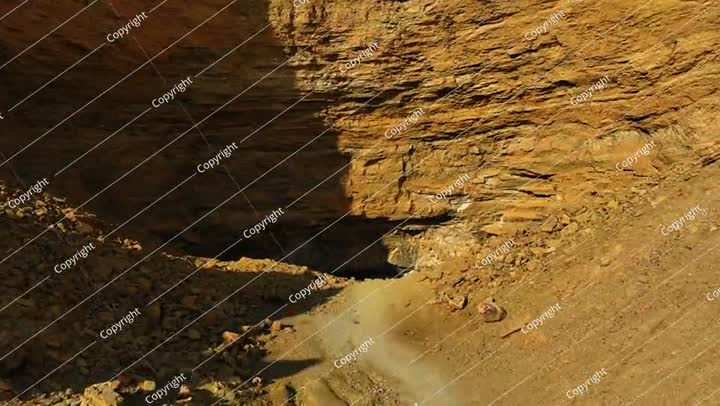 Aerial: Drone Forward Tranquil View Of Dark Cave In Desert On Sunny Day -
