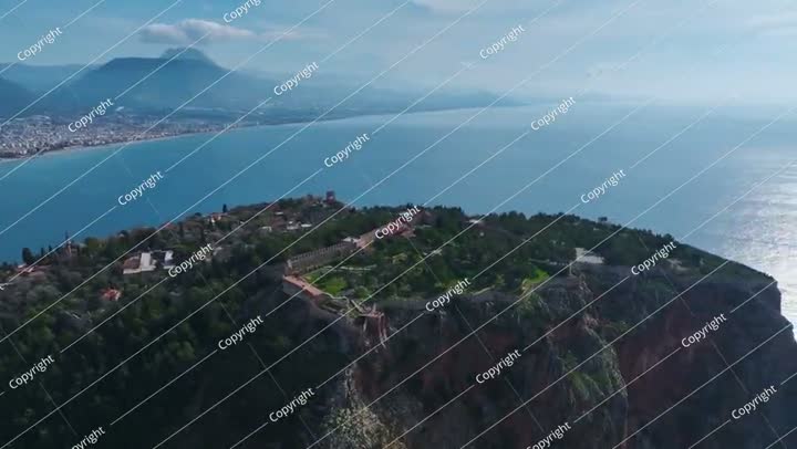 فيديو جوي لجدار قلعة عتيق على حافة جبل، مغطى بالخضرة