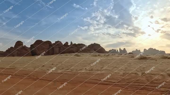 منظر من السيارة أثناء القيادة في منطقة الحجر الأثرية، صحراء مسطحة مع القليل من الأشجار الصغيرة.