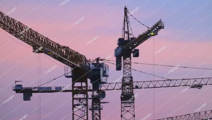 الكثير من الرافعات تعمل على البناء الضخم في المملكة العربية السعودية عند غروب الشمس