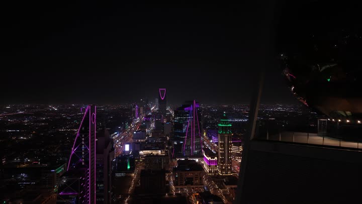 The growth and urban development in the Kingdom of Saudi Arabia, drone photography of the architectural art of Riyadh at night, the towers and skyscrapers, facilities, and commercial buildings in the Al Olaya district, the civilizational progress in cities and neighborhoods, famous tourist attractions.
