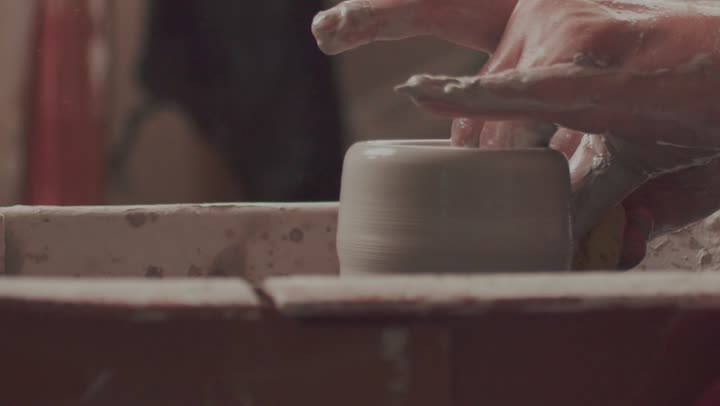 Working in the pottery industry, crafts and handmade industries that are part of the rich Saudi heritage, ceramic vessels made from clay, the creation of decorated clay jars, a close-up shot of the hands of a Saudi Arabian Gulf man making pottery.