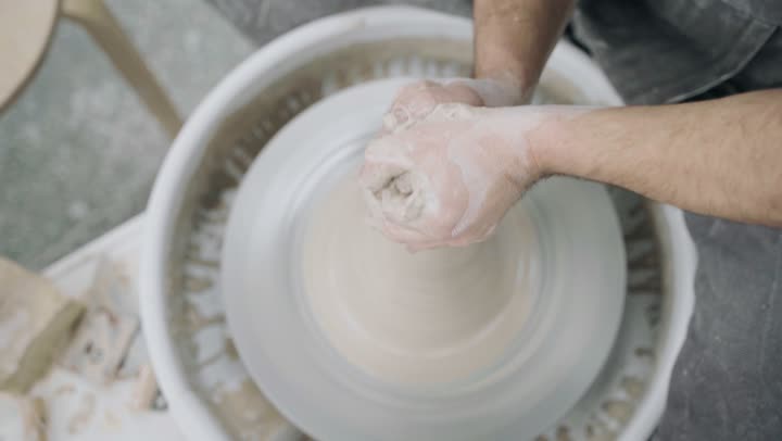 Working in the pottery industry, crafts and handmade industries that are part of the rich Saudi heritage, ceramic vessels made from clay, the creation of decorated clay jars, a close-up shot of the hands of a Saudi Arabian Gulf man making pottery.