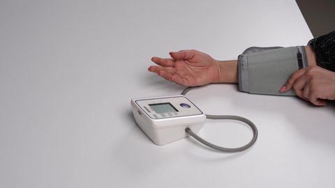 ضرورة المتابعة الدورية وفحص التروية الدموية بشكل مستمر, الأجهزة المتنقلة الحديثة للتحاليل المنزلية، الرعاية الصحية والفحوصات الطبية السريعة, تصوير مقرب لشابة عربية خليجية إماراتية ترتدي العباءة السوداء تقيس ضغط الدم باستخدام الميزان الالكتروني، خلفية بيضاء