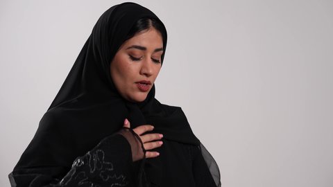 إمرأة سعودية مصابة بتضرر في مجرى الهواء، أجهزة استنشاق خاصة بمرضى الجهاز التنفسي والرئتين، تصوير مقرب لشابة عربية خليجية إماراتية محجبة ترتدي العباءة تعاني من أزمة تنفس تحسسية، استخدام جهاز الرذاذ الخاص بمرض الربو، الشعور بالاختناق وضيق في النفس، خلفية بيضاء