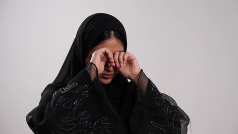 The importance of going to bed early and following a healthy routine, gestures of fatigue and exhaustion and the need to take a break, the feeling of boredom and lethargy, a Saudi woman covering her mouth with her hand showing expressions of drowsiness and laziness, a close-up shot of a young Emirati Gulf Arab woman wearing a hijab and an abaya yawning, white background.