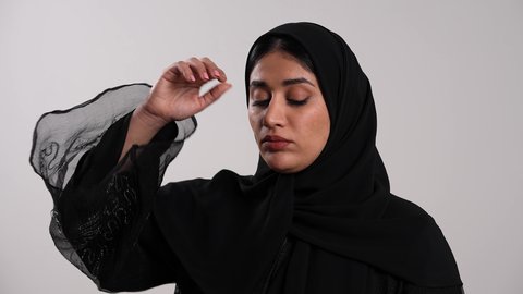 استخدام مقياس الحرارة الفموي لتحديد درجة حرارة الجسم، أهمية زيارة الطبيب وأخذ العلاج المناسب، امرأة سعودية تشعر بالمرض والإرهاق، إيماءات التعب والحاجة للراحة، تصوير مقرب لشابة عربية خليجية إماراتية محجبة ترتدي العباءة تقيس حرارتها بالميزان الرقمي، خلفية بيضاء