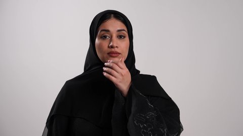 معالجة حالات التهاب العصب البصري وأخذ العلاج اللازم، العناية بالعين والحاجة لتعقيمها بشكل مستمر، شابة سعودية تستخدم القطرة العينية حسب تعليمات الطبيب، تصوير مقرب لامرأة عربية خليجية إماراتية محجبة ترتدي العباءة السوداء تقوم بوضع القطرات في عينها، خلفية بيضاء