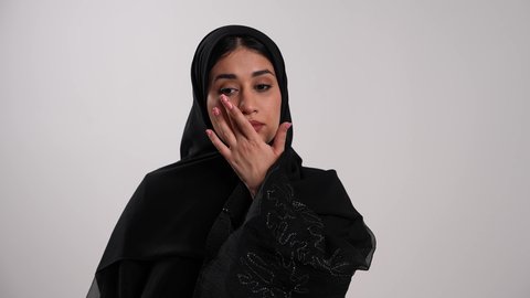 العناية بالعين والحاجة لتعقيمها بشكل مستمر، معالجة حالات التهاب العصب البصري وأخذ العلاج اللازم، شابة سعودية تستخدم القطرة العينية حسب تعليمات الطبيب، تصوير مقرب لامرأة عربية خليجية إماراتية محجبة ترتدي العباءة السوداء تقوم بوضع القطرات في عينها، خلفية بيضاء