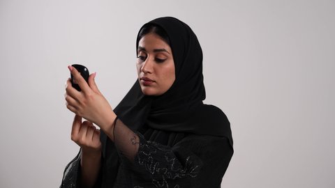 شابة سعودية مصابة بحالة مرضية مزمنة, المتابعة الدورية لمرضى داء السكري, تصوير مقرب لامرأة عربية خليجية إماراتية ترتدي العباءة تقوم بوخز اصبعها, الفحوصات الطبية السريعة لمعرفة نسبة السكر في الدم، استخدام الأجهزة الالكترونية للتحاليل المنزلية، خلفية بيضاء