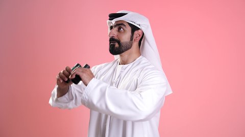 حب المغامرة والاستكشاف،  التخطيط المستقبلي للأهداف والطموحات، تصوير مقرب لشاب عربي خليجي اماراتي يرتدي الكندورة والغترة ينظر من خلال المنظار ثنائي العينين بايماءات الاستغراب،البحث عن شيء ما وتوسيع مجال الرؤية، رؤية الاشياء البعيدة عبر التلسكوب، خلفية وردية