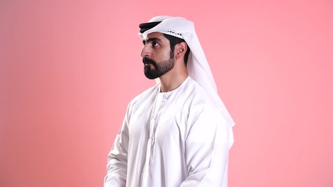 البحث عن شيء ما وتوسيع مجال الرؤية، التخطيط المستقبلي للأهداف والطموحات، تصوير مقرب لشاب عربي خليجي اماراتي يرتدي الكندورة والغترة ينظر من خلال المنظار ثنائي العينين بايماءات الاستغراب، حب المغامرة والاستكشاف، رؤية الاشياء البعيدة عبر التلسكوب، خلفية وردية