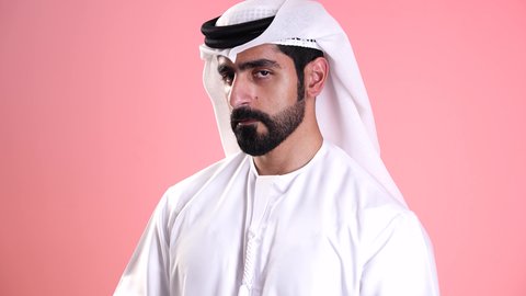 رؤية الاشياء البعيدة عبر التلسكوب،  التخطيط المستقبلي للأهداف والطموحات، تصوير مقرب لشاب عربي خليجي اماراتي يرتدي الكندورة والغترة ينظر من خلال المنظار ثنائي العينين بايماءات الاستغراب، حب المغامرة والاستكشاف، البحث عن شيء ما وتوسيع مجال الرؤية، خلفية وردية