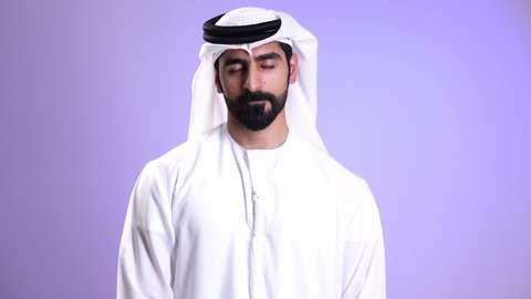 النهي عن فعل أمر معين, طلب عدم التدخل, تصوير مقرب لرجل عربي خليجي إماراتي يرتدي الكندورة والغترة البيضاء يرفع أصبعه السبابة بتعابير المنع والرفض وعدم الموافقة, النظر الى الكاميرا بايماءات الانزعاج، خلفية موف