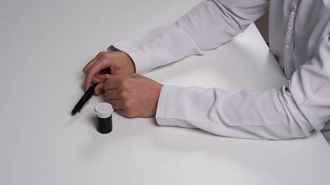 ضرورة التحليل الدوري لمرضى داء السكري, الإصابة بالحالات المرضية المزمنة, تصوير مقرب علوي لرجل عربي خليجي إماراتي يقوم بفحص نسبة السكر في الدم لشخص آخر, الرعاية الصحية والفحوصات الطبية السريعة, الأجهزة الالكترونية الحديثة للتحاليل المنزلية، خلفية بيضاء