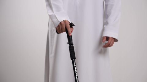 دعم ذوي الحالات الخاصة ودمجهم في المجتمع الإماراتي،توفير التحفيز والتشجيع النفسي للمكفوفين، التعرض لضرر في العيون وفقد البصر، أذية الشبكية والإصابة بالعمى، تصوير مقرب لشاب عربي خليجي إماراتي ضرير يستخدم العكاز ، خلفية بيضاء