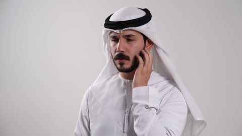 الإحساس بالمرض والإرهاق، إيماءات التعب والحاجة للراحة، أهمية زيارة الطبيب وأخذ العلاج المناسب، استخدام مقياس الحرارة الفموي لتحديد درجة حرارة الجسم، تصوير مقرب لشاب عربي خليجي إماراتي يرتدي الكندورة والغترة يقيس حرارته عن طريق الميزان الرقمي، خلفية بيضاء