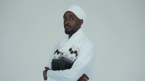 Looking at the camera with gestures of pride and confidence, love and belonging to the homeland, boasting and pride in Arab customs, celebrating independence on January 1, commemorating Sudan's National Day in 1956, love for the homeland and pride in it, an Arab Sudanese man wearing a tobe and a white turban stands confidently and upright, with a white background.