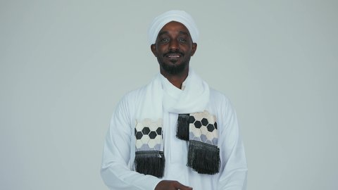 الوقوف بثقة وايدي متقاطعة، ايماءات الاعتزاز والثقة، الاحتفال بالاستقلال ١ يناير، استذكار اليوم الوطني السوداني ١٩٥٦ م، حب الوطن والاعتزاز به، بورتريه مقرب لرجل عربي سوداني يرتدي التوب والشال والعمه البيضاء يقف بثقة واستقامة، خلفية بيضاء