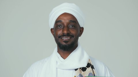 الاحتفال باليوم الوطني الإماراتي 2 ديسمبر ، ايماءات السعادة والسرور، مفهوم الحب و الانتماء للبلاد, الأعياد و المناسبات الوطنية, بورتريه لرجل عربي سوداني يرتدي العمامة والجلابية والشال يحمل علم الإمارات العربية المتحدة, خلفية بيضاء