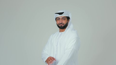 Standing with crossed arms, elegance and attention to appearance, a portrait of an Emirati Gulf Arab man wearing a kandura and ghutrah looking at the camera with gestures of self-confidence, white background.