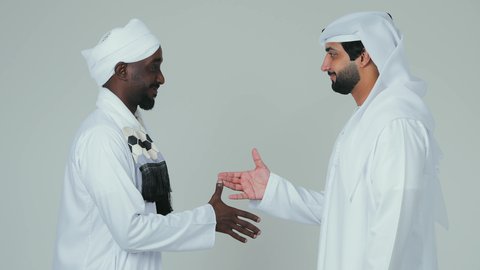 اتفاقية عمل جديده بين الشركاء، صفقة جماعية مشتركة ناجحة،،بورتريه رجل عربي اماراتي يرتدي الكندورة و الغترةيقوم بمصافحة رجل سوداني يرتدي الجلابية و العمامة و الشال،اتفاقيات بين البلدان ،تعارف و صداقات وعلاقات جديدة ، لفية بيضاء