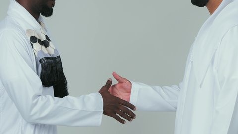 اتفاقية عمل جديده بين الشركاء، صفقة جماعية مشتركة ناجحة،بورتريه مقرب لرجل عربي اماراتي يرتدي الكندورة و الغترةيقوم بمصافحة رجل سوداني يرتدي الجلابية و العمامة و الشال،اتفاقيات بين البلدان ،تعارف و صداقات وعلاقات جديدة ، لفية بيضاء