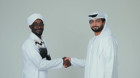 اتفاقية عمل جديده بين الشركاء، صفقة جماعية مشتركة ناجحة،،بورتريه رجل عربي اماراتي يرتدي الكندورة و الغترةيقوم بمصافحة رجل سوداني يرتدي الجلابية و العمامة و الشال،اتفاقيات بين البلدان ،تعارف و صداقات وعلاقات جديدة ، لفية بيضاء