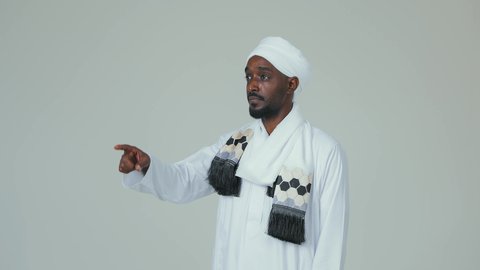 الاشارة باصبع السبابة الى شيء معين، بورتريه لرجل عربي سوداني يرتدي الجلابية ويضع العمامة والشال يقف باستقامة ويشير إلى شيء ما، الوقوف بثقة والاهتمام بالمظهر الخارجي، خلفية بيضاء