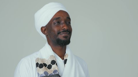 ايماءات السرور والسعادة،  بورتريه مقرب لرجل عربي سوداني يرتدي الجلابية ويضع العمامة والشال يقف باستقامة وينظر إلى شيء ما، الوقوف بثقة والاهتمام بالمظهر الخارجي،خلفية بيضاء