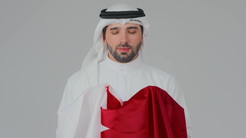 الانتماء الوطني والولاء لدولة قطر، إحياء ذكرى تأسيس الدولة، الاحتفال باليوم الوطني القطري 18 ديسمبر، ثقافات وطنية و رموز, حب الوطن والانتماء إليه،  بورتريه لرجل عربي خليجي قطري يرتدي الثوب التقليدي والغترة يحمل علم قطر ويشمه بفخر واعتزاز،  خلفية بيضاء