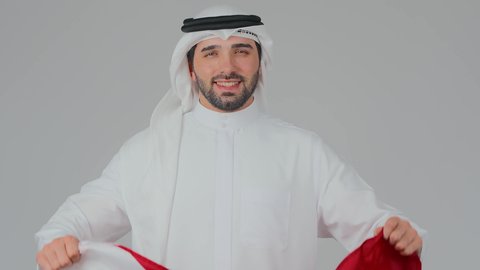 تعابير الفخر والاعتزاز، اعياد وطنية ومناسبات، إحياء ذكرى تأسيس الدولة، الاحتفال باليوم الوطني القطري 18 ديسمبر، ثقافات وطنية و رموز, حب الوطن والانتماء إليه،  بورتريه مقرب لرجل عربي خليجي قطري يرتدي الثوب التقليدي والغترة يحمل العلم القطري،  خلفية بيضاء