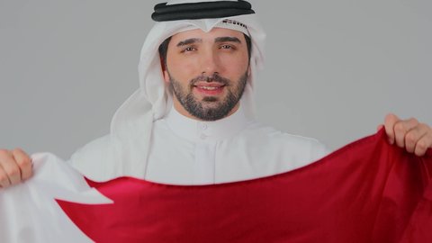 National holidays and occasions, commemorating the founding of the state, celebrating Qatar National Day on December 18, national cultures and symbols, love for the homeland and belonging to it, a close-up portrait of a Qatari Gulf Arab man wearing traditional attire and a ghutrah holding the Qatari flag, white background.