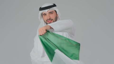 محبة الوطن والاعتزاز به، الاحتفال باليوم الوطني الإماراتي, الأعياد و المناسبات الوطنية, بورتريه مقرب لرجل عربي خليجي إماراتي يرتدي الكندورة والغترة البيضاء يقوم بوضع علم الإمارات العربية المتحدة على الاكتاف, إحياء ذكرى استقلال البلاد 1971 م، خلفية بيضاء