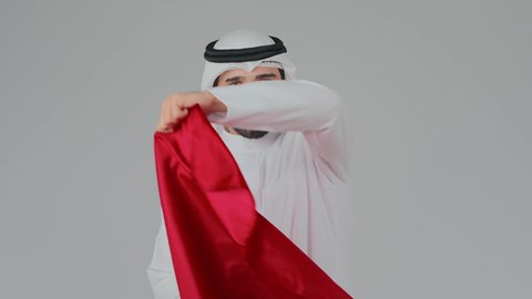 الاعتزاز والفخر بالتراث والثقافة في دولة قطر، إحياء ذكرى تأسيس الدولة، الاحتفال باليوم الوطني القطري 18 ديسمبر، ثقافات وطنية و رموز, حب الوطن والانتماء إليه،  بورتريه لرجل عربي خليجي قطري يرتدي الثوب التقليدي والغترة يضع على اكتافه العلم القطر،  خلفية بيضاء