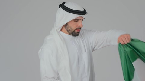 يوم العلم 3 نوفمبر، الاحتفال باليوم الوطني الإماراتي, الأعياد و المناسبات الوطنية, بورتريه مقرب لرجل عربي خليجي إماراتي يرتدي الكندورة والغترة البيضاء يقوم بوضع علم الإمارات العربية المتحدة على الاكتاف, إحياء ذكرى استقلال البلاد 1971 م، خلفية بيضاء