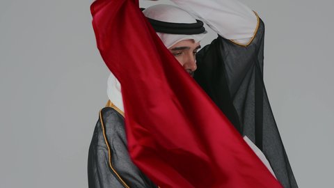 حب الوطن والانتماء إليه، رموز وثقافات وطنية, الاحتفال باليوم الوطني القطري 18 ديسمبر، إحياء ذكرى تأسيس الدولة، تصوير لرجل عربي خليجي قطري يرتدي الثوب التقليدي والغترة يضع على اكتافه العلم القطر بايماءات الفخروالاعتزاز، حب الوطن والانتماء إليه،  خلفية بيضاء